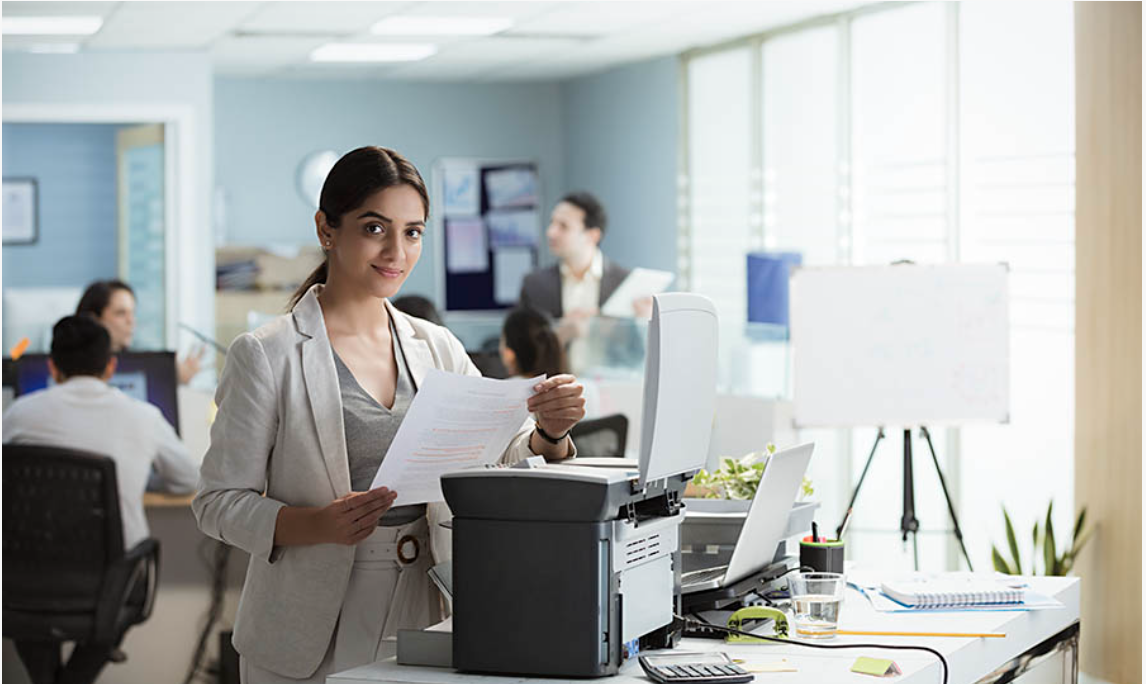 Woman at office printer reviewing documents