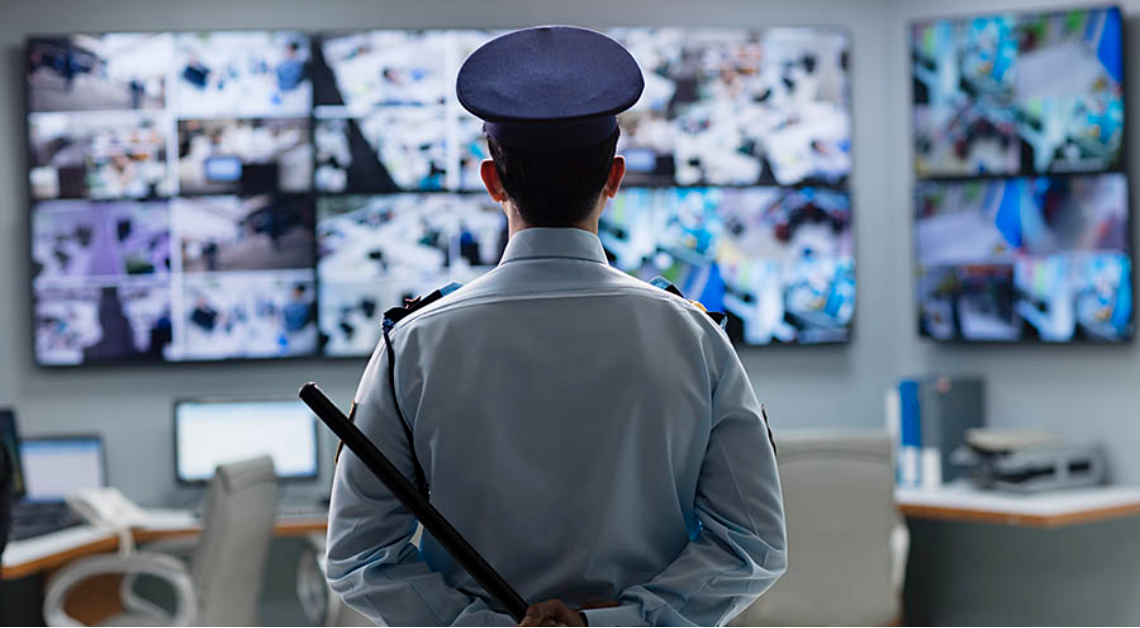 Security officer in front of CCTV monitor wall
