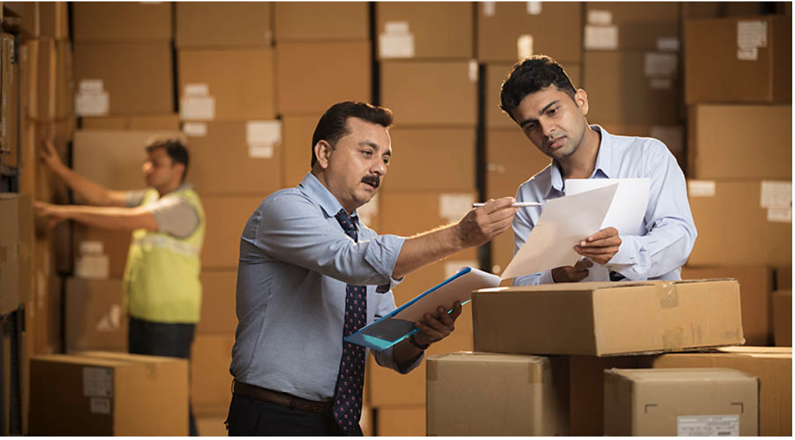 Warehouse managers reviewing inventory among boxes