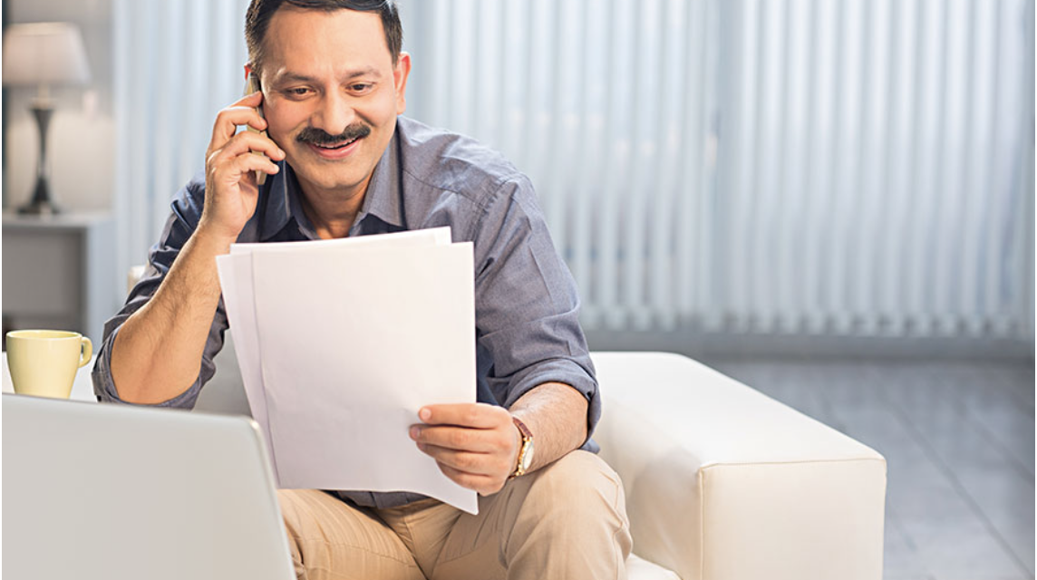 Man on phone reviewing documents at home